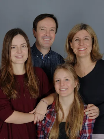Vierköpfige Familie lächelt gemeinsam in die Kamera